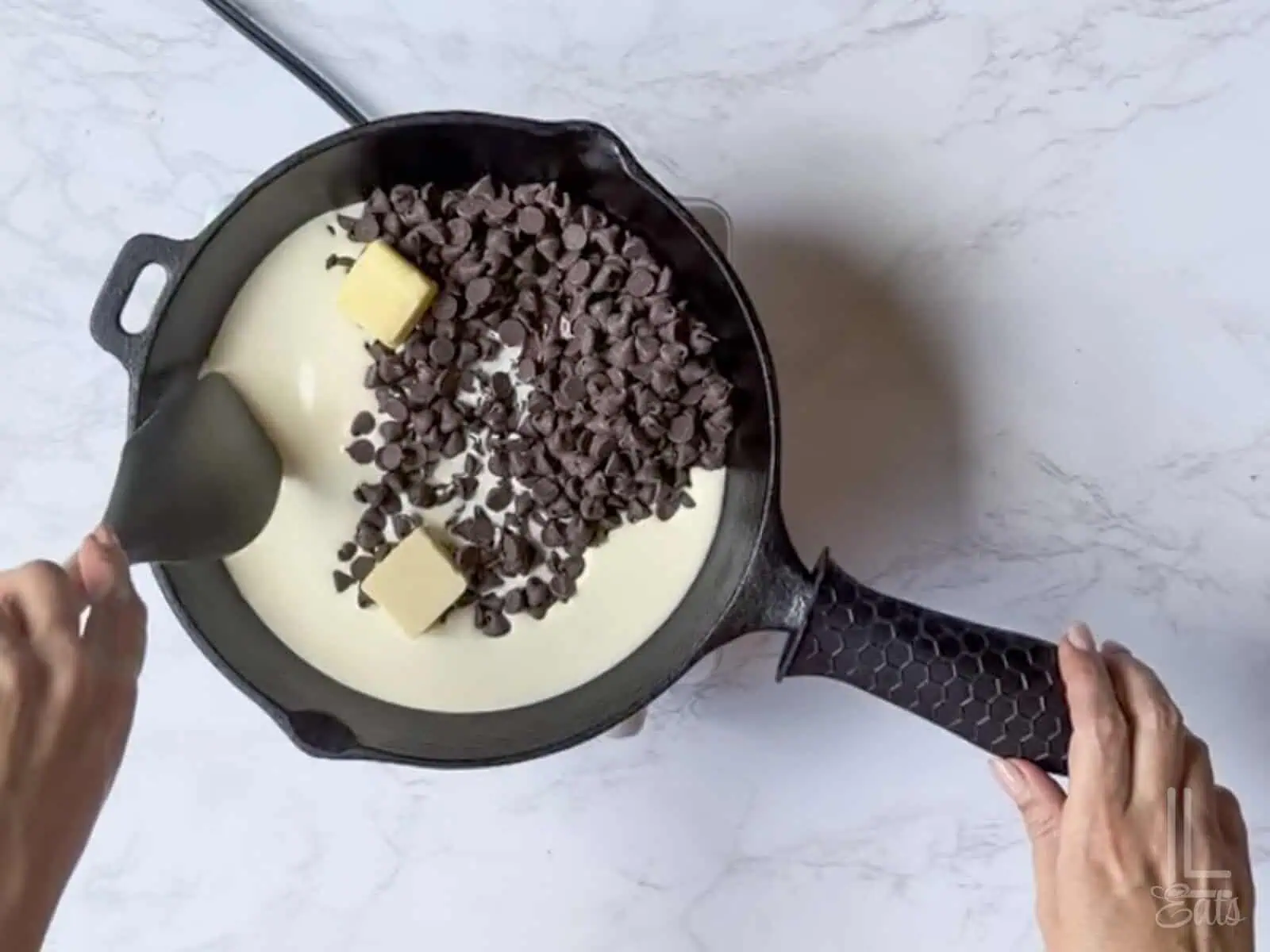 heavy cream, chocolate chips, and butter added to a cast iron skillet.