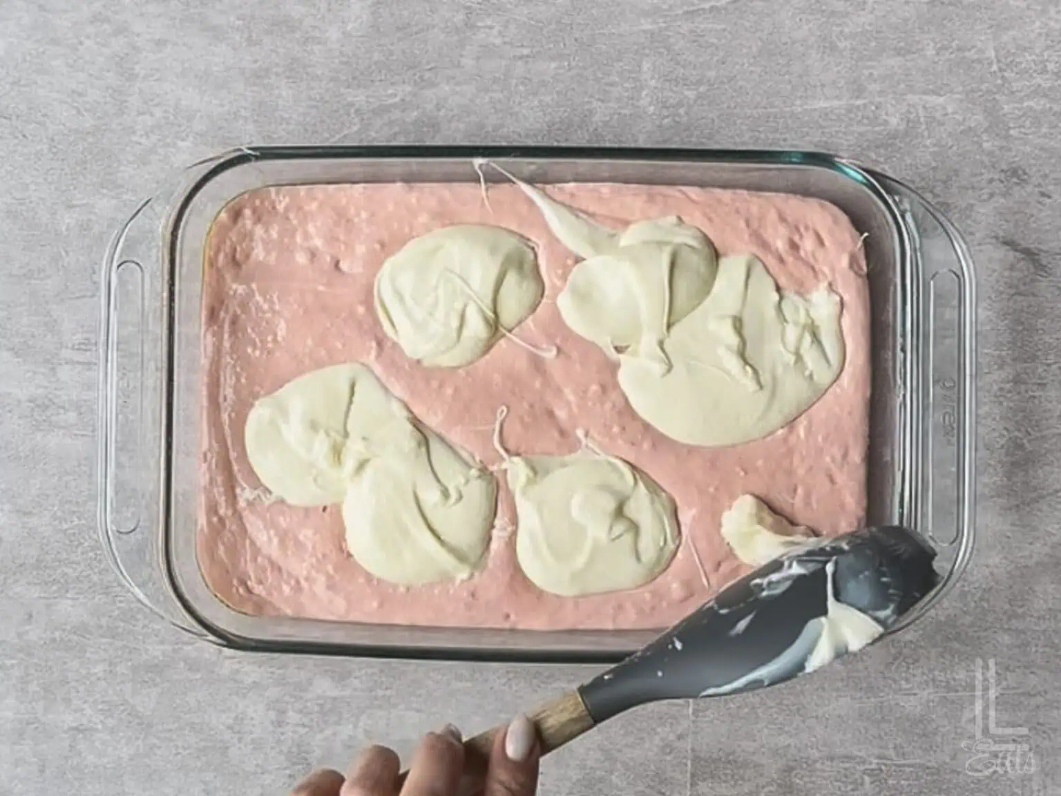 spooning dollops of cream cheese mixture over cake batter in the pan.