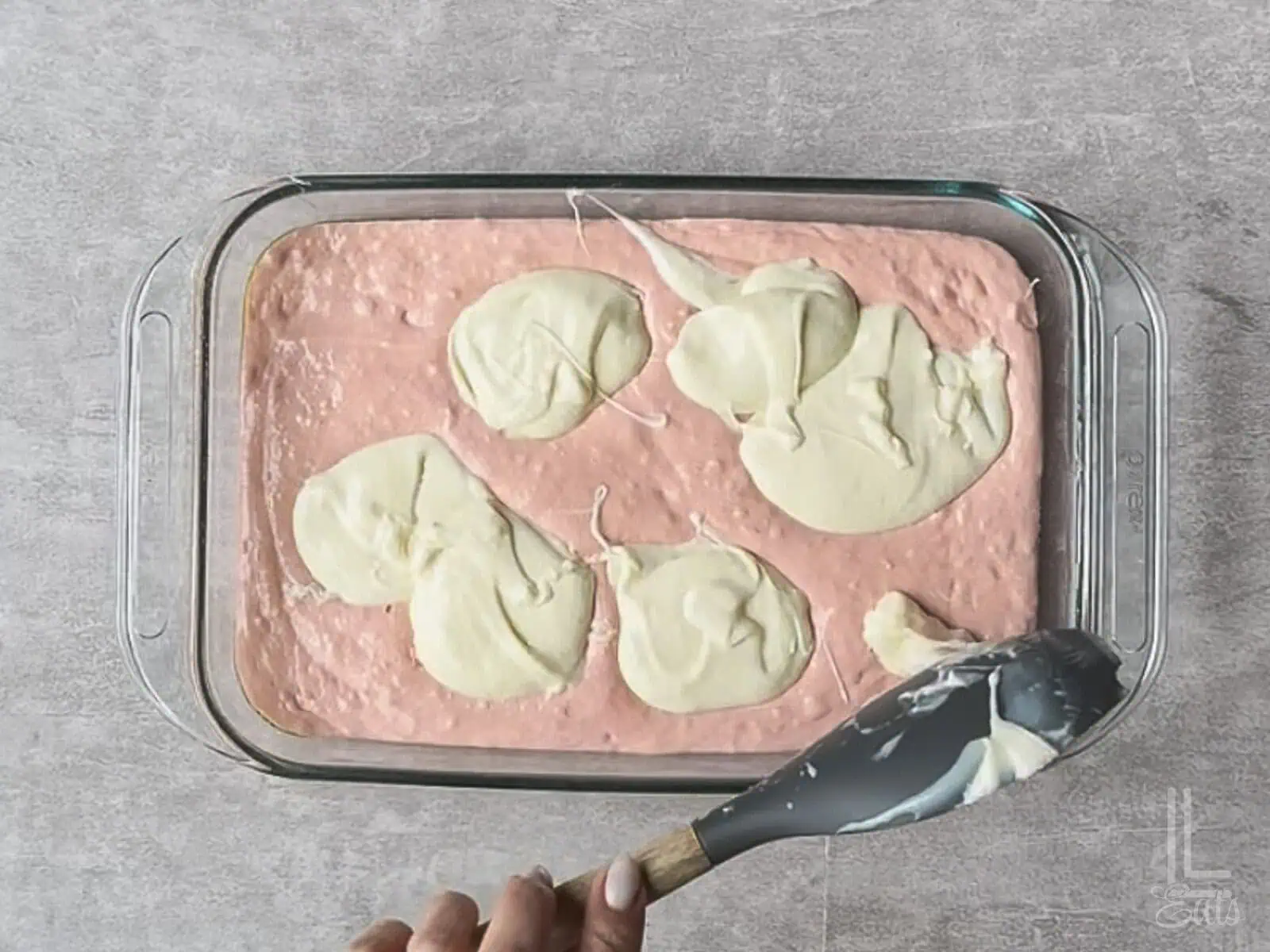 spooning dollops of cream cheese mixture over cake batter in the pan.