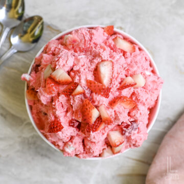 bowl of strawberry fluff salad topped with fresh strawberries.