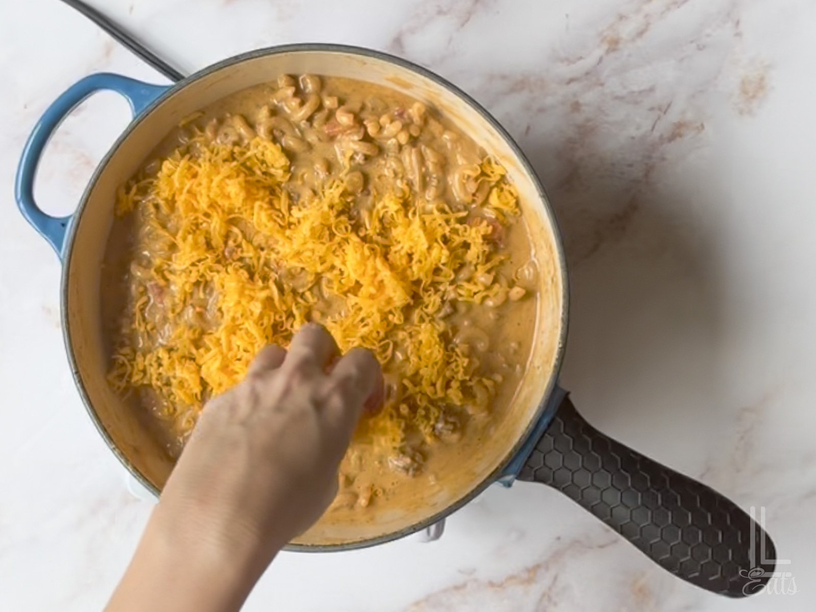 sprinkling cheddar cheese over the top of the cooked taco mac and cheese.