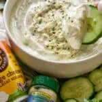 Creamy cottage cheese ranch dip with cucumber slices and herbs in a bowl.