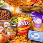 Walking Taco Casserole with Fritos, cheese, beef, and toppings on a plate.