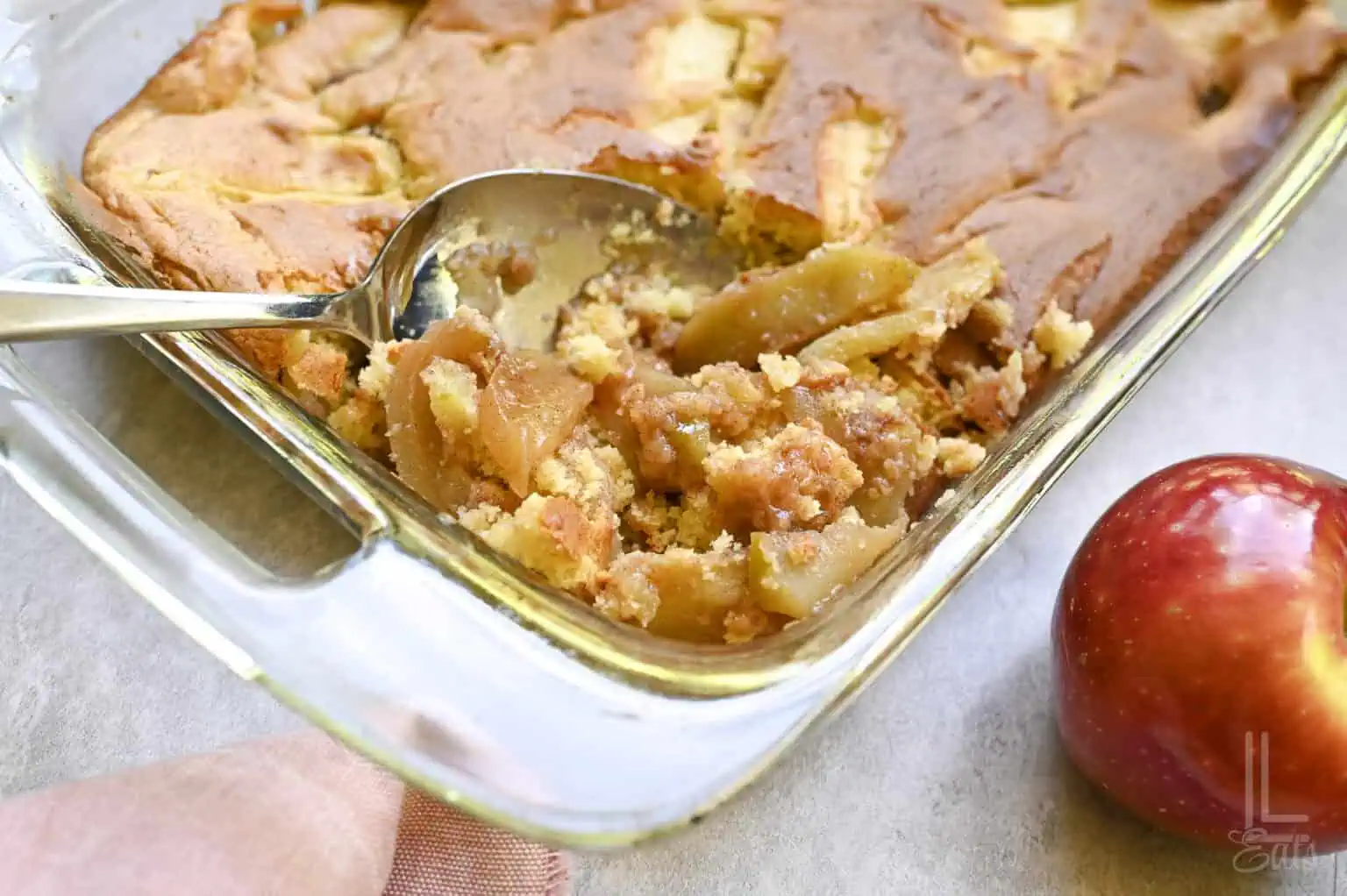 spoon in a baking dish of apple cobbler made with cake mix.