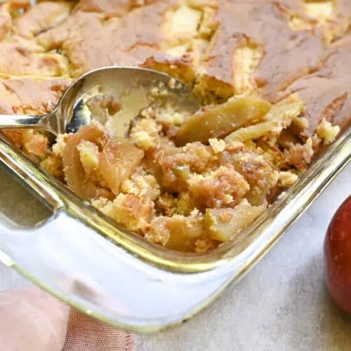 spoon in a baking dish of apple cobbler made with cake mix.
