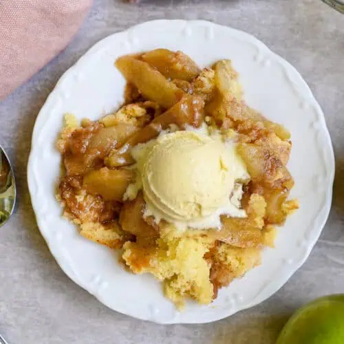 serving of cake mix apple cobbler with a scoop of vanilla ice cream on top.