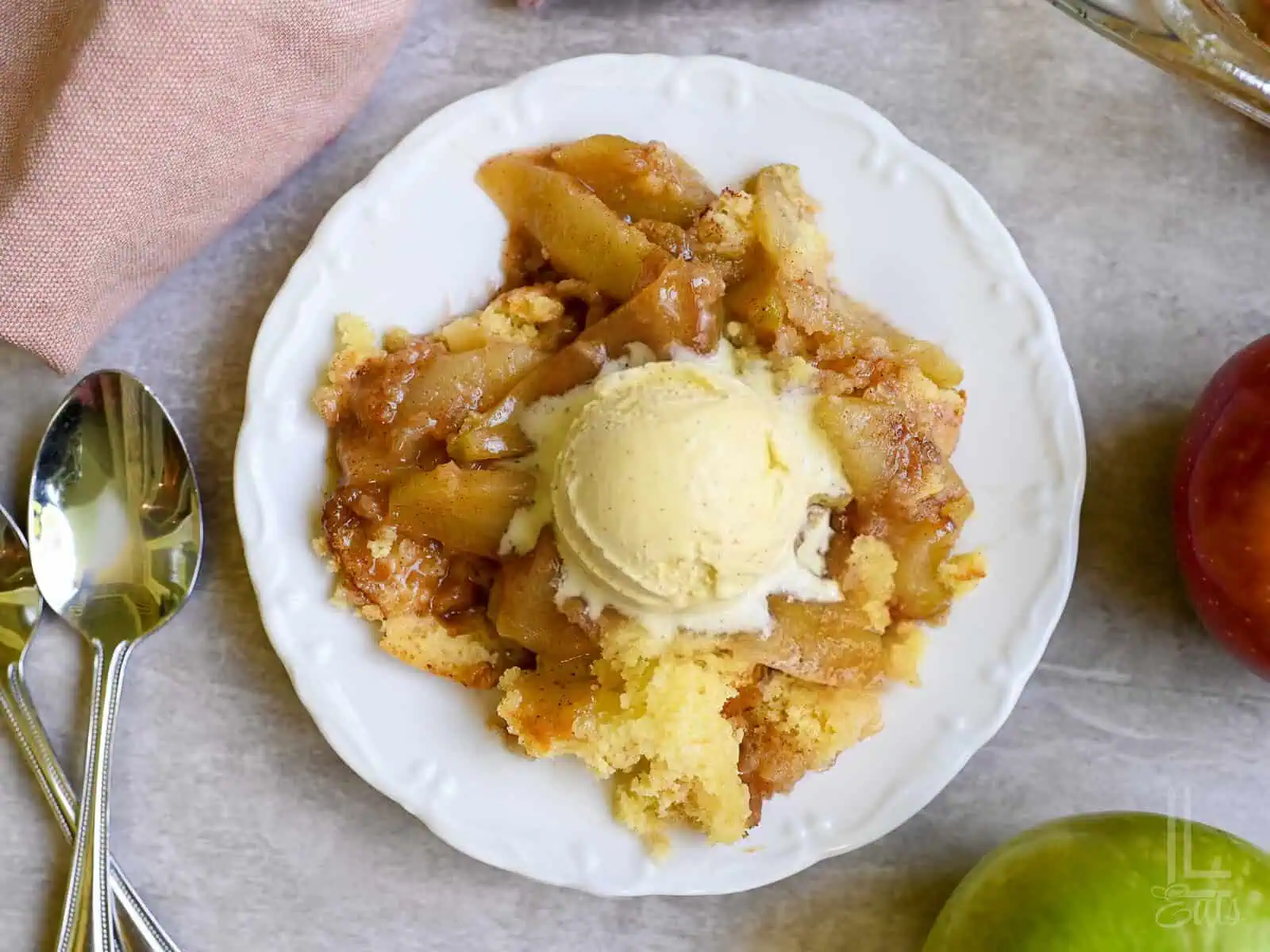 serving of cake mix apple cobbler with a scoop of vanilla ice cream on top.