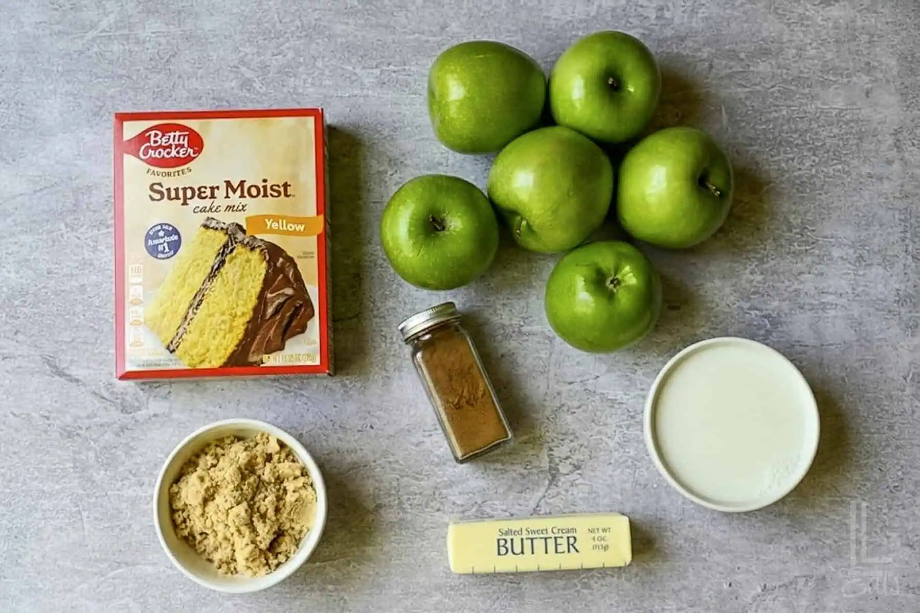 ingredients for easy apple cobbler (cake mix, apples, brown sugar, cinnamon, butter, and milk).