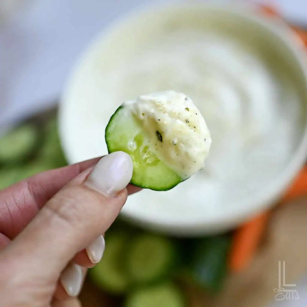 holding cottage cheese ranch dip on a cucumber slice.