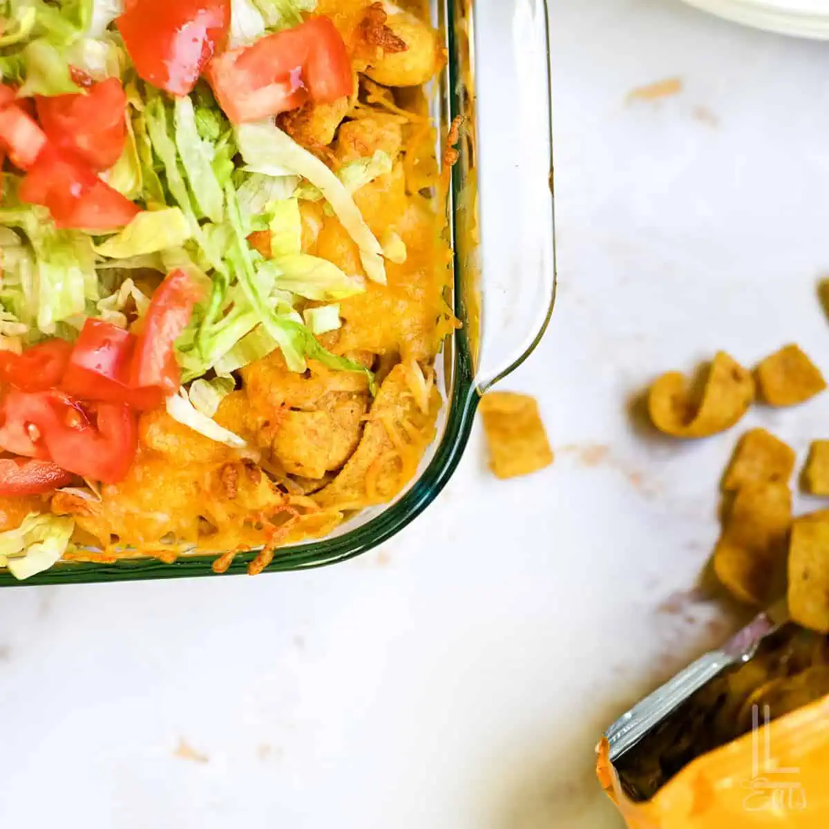 corner of walking taco casserole, next to a bag of corn chips.