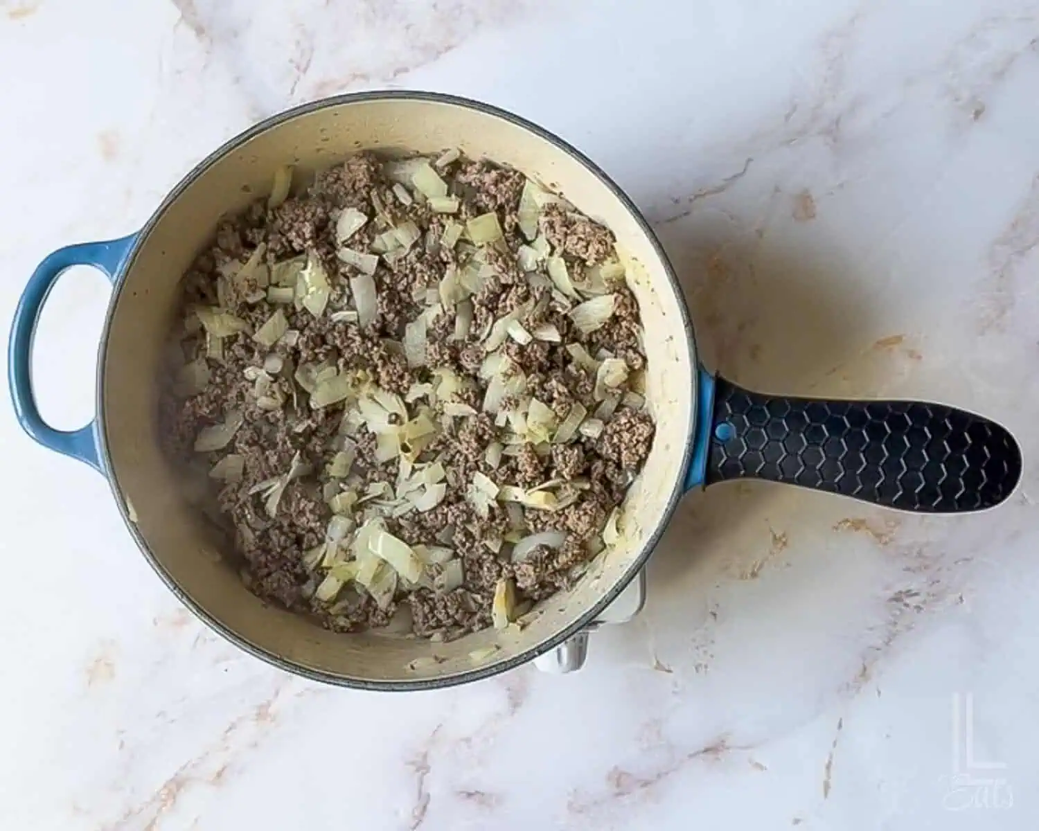 ground beef and onions cooking in a large skillet.