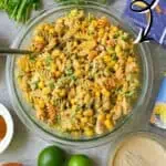 Mexican street corn pasta salad with lime dressing and colorful ingredients.