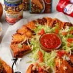 Delicious taco crescent ring with crispy crust, fresh salad, and salsa dip.