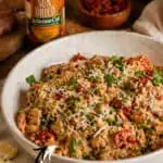 Creamy Marry Me Chicken Thighs in a white bowl with herbs and cheese.