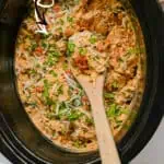 Creamy Crock Pot Marry Me Chicken with herbs and shredded cheese in a slow cooker.