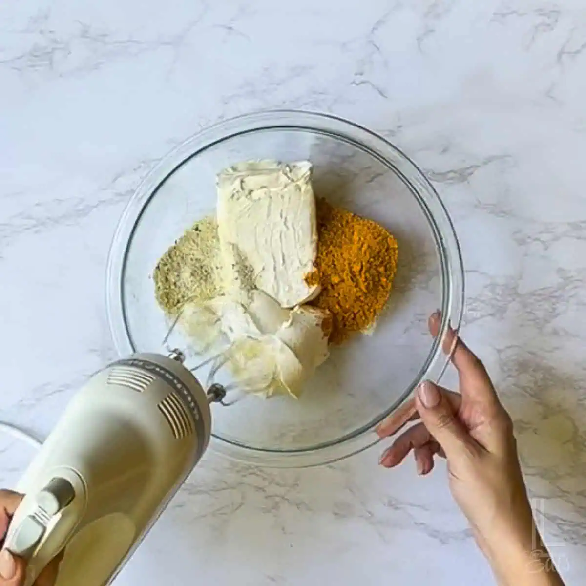 taco seasoning, ranch seasoning mix, sour cream, and cream cheese mixing together in a bowl.