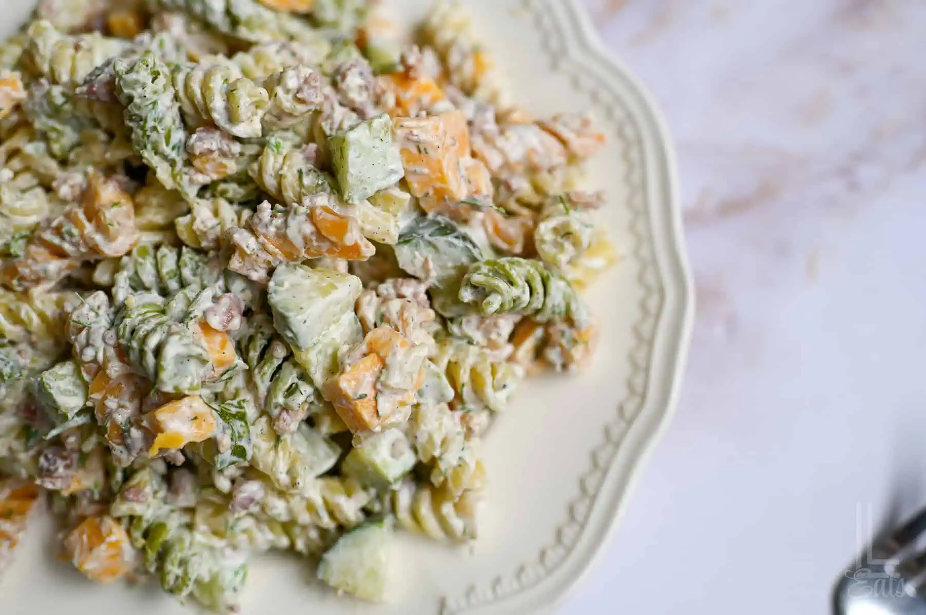 plate of dill pickle pasta salad with cheddar cheese and chopped pickles.