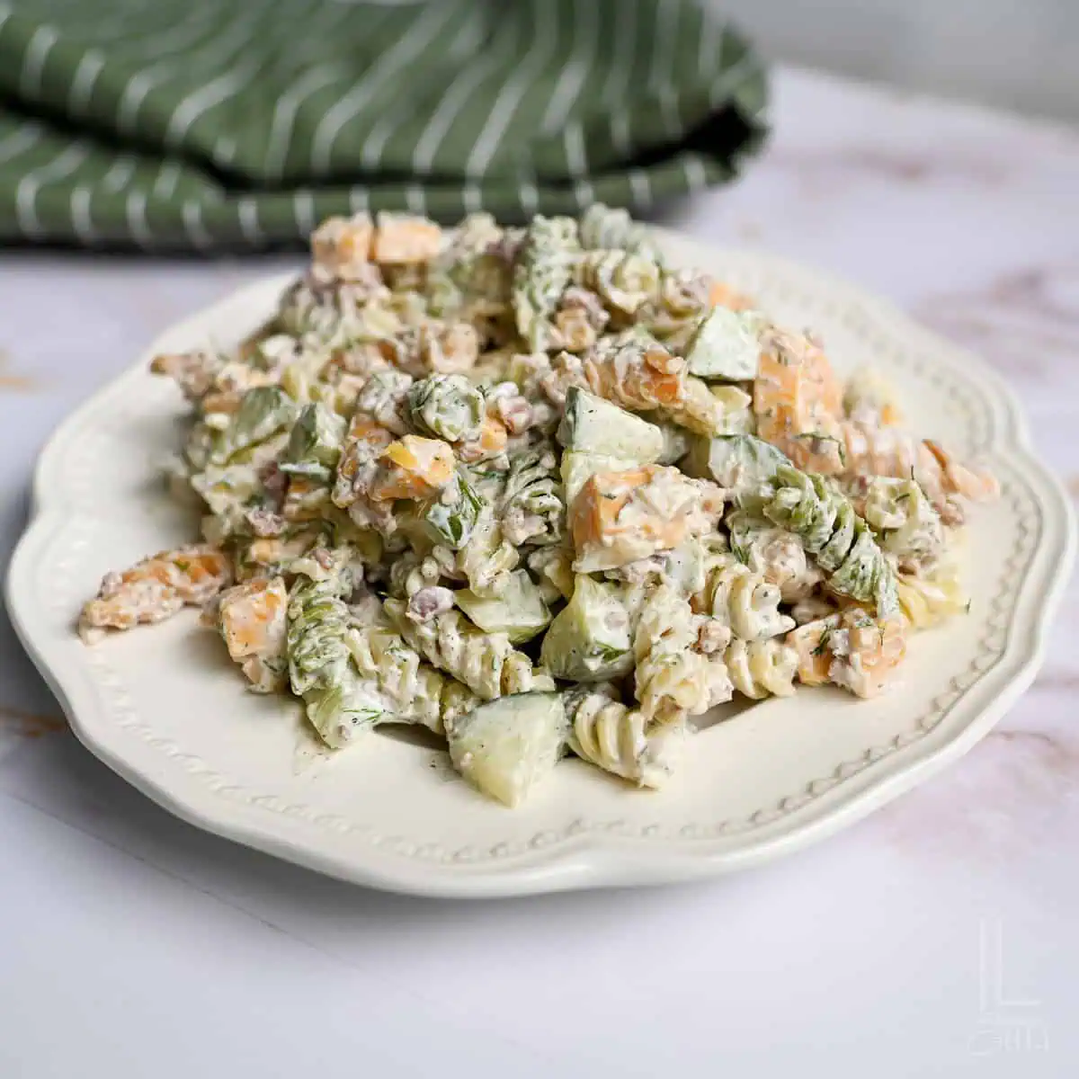 heaping plate of creamy dill pickle pasta salad loaded with rotini and cheese.
