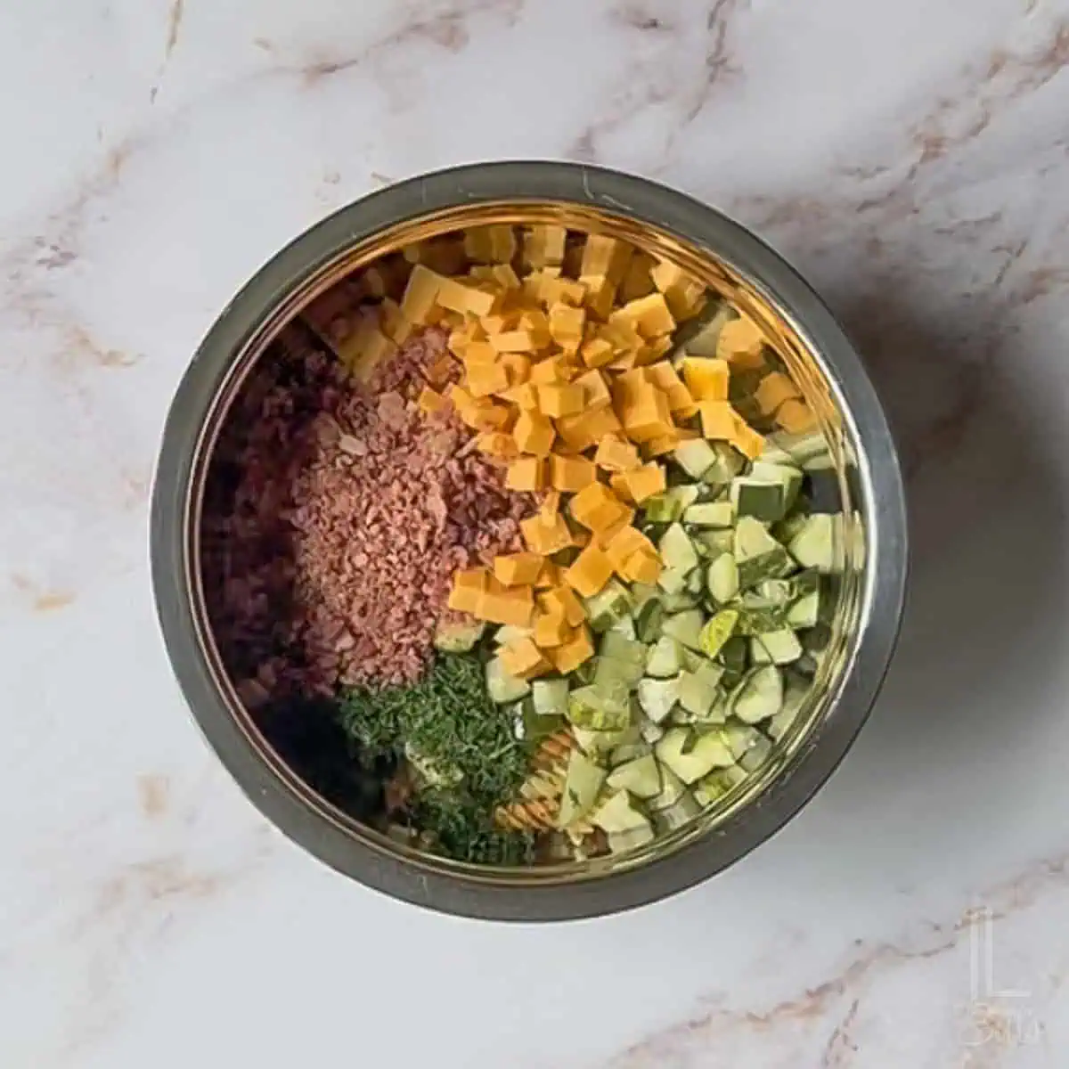 adding cheddar cheese, bacon, chopped pickles, and dill to the pasta.