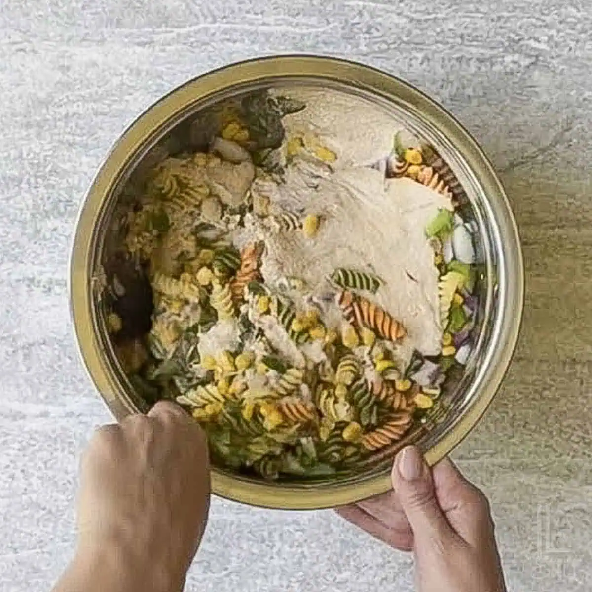 adding dressing to the mexican street corn pasta salad.