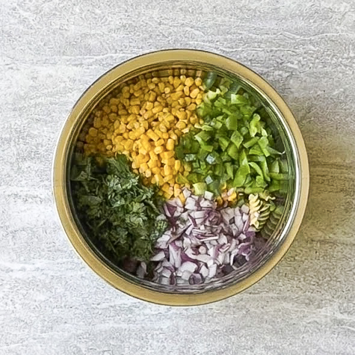 veggies and cooked rotini added to a large bowl.