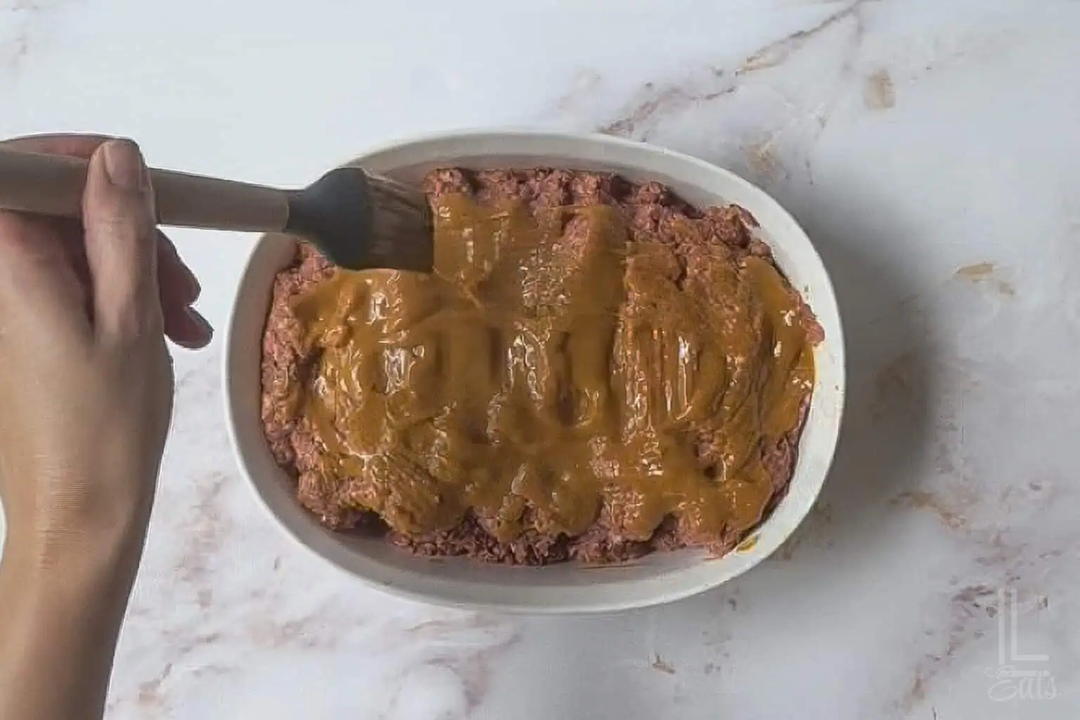 brushing a ketchup/mustard/brown sugar sauce over the uncooked meatloaf.