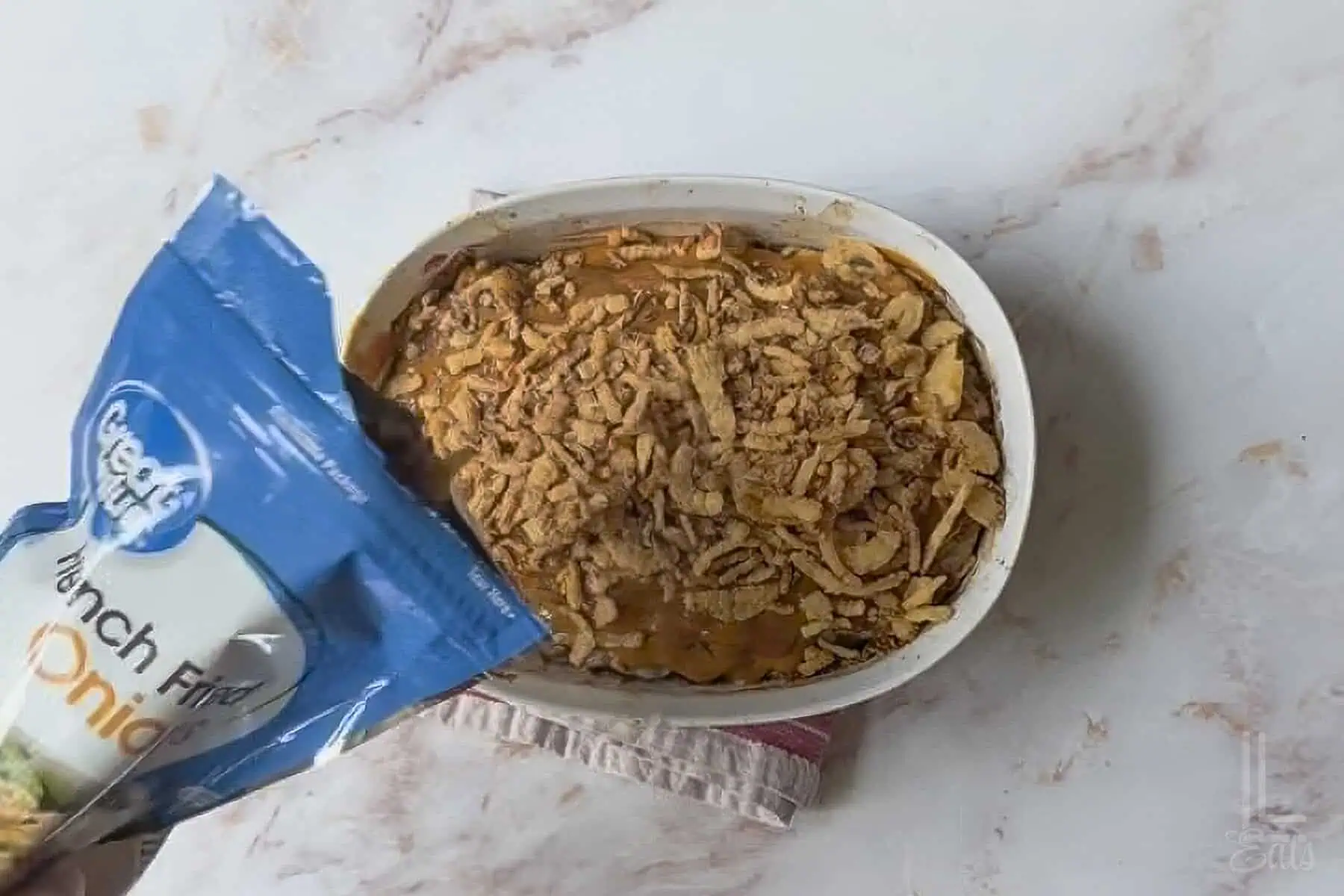 pouring crispy fried onions over the top of the cooked meatloaf.