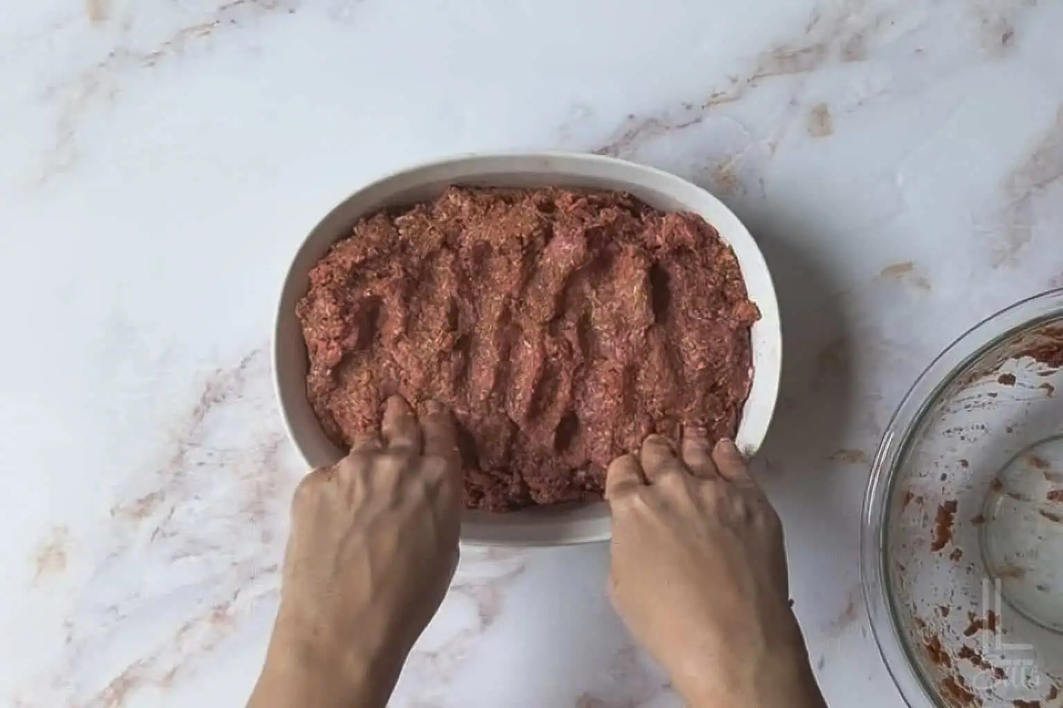 shaping the Lipton onion soup meatloaf in a corningware oval dish.