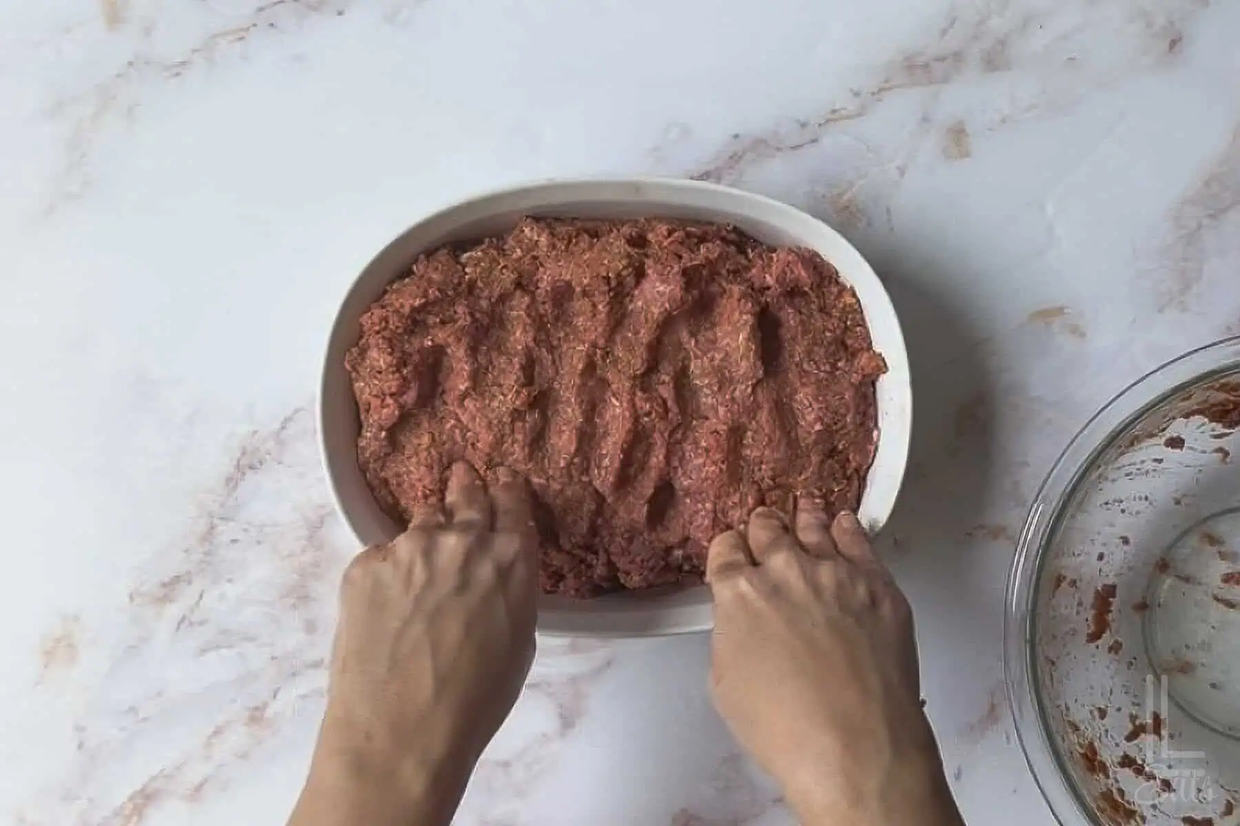 shaping the Lipton onion soup meatloaf in a corningware oval dish.