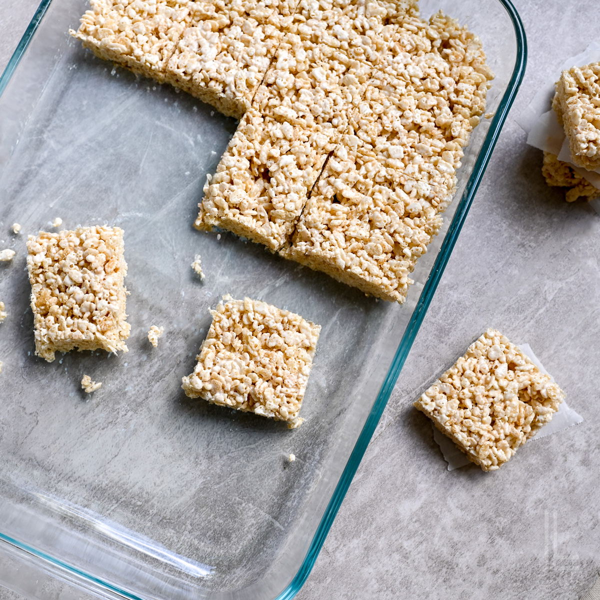 baking dish with cut rice krispie treats scattered around it.