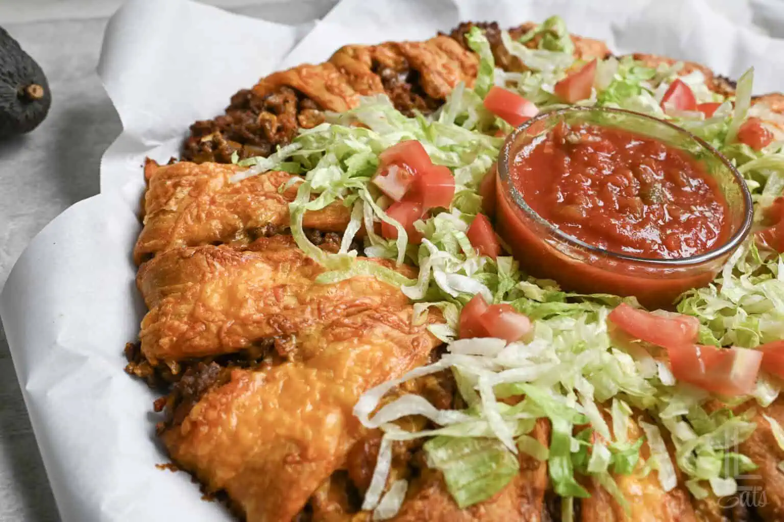 a baked taco crescent ring with a cheesy crust and toppings.