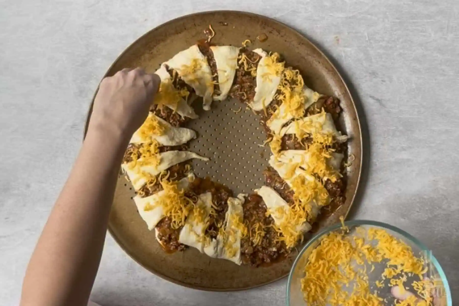 covering the unbaked taco crescent ring in shredded cheddar cheese.
