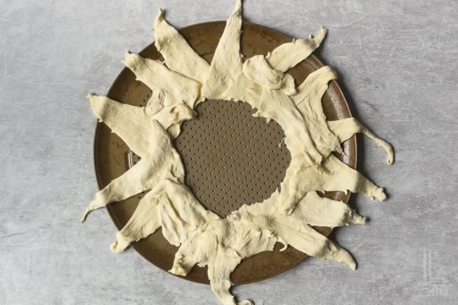 crescent roll dough in a sunburst shape on a round pizza pan.