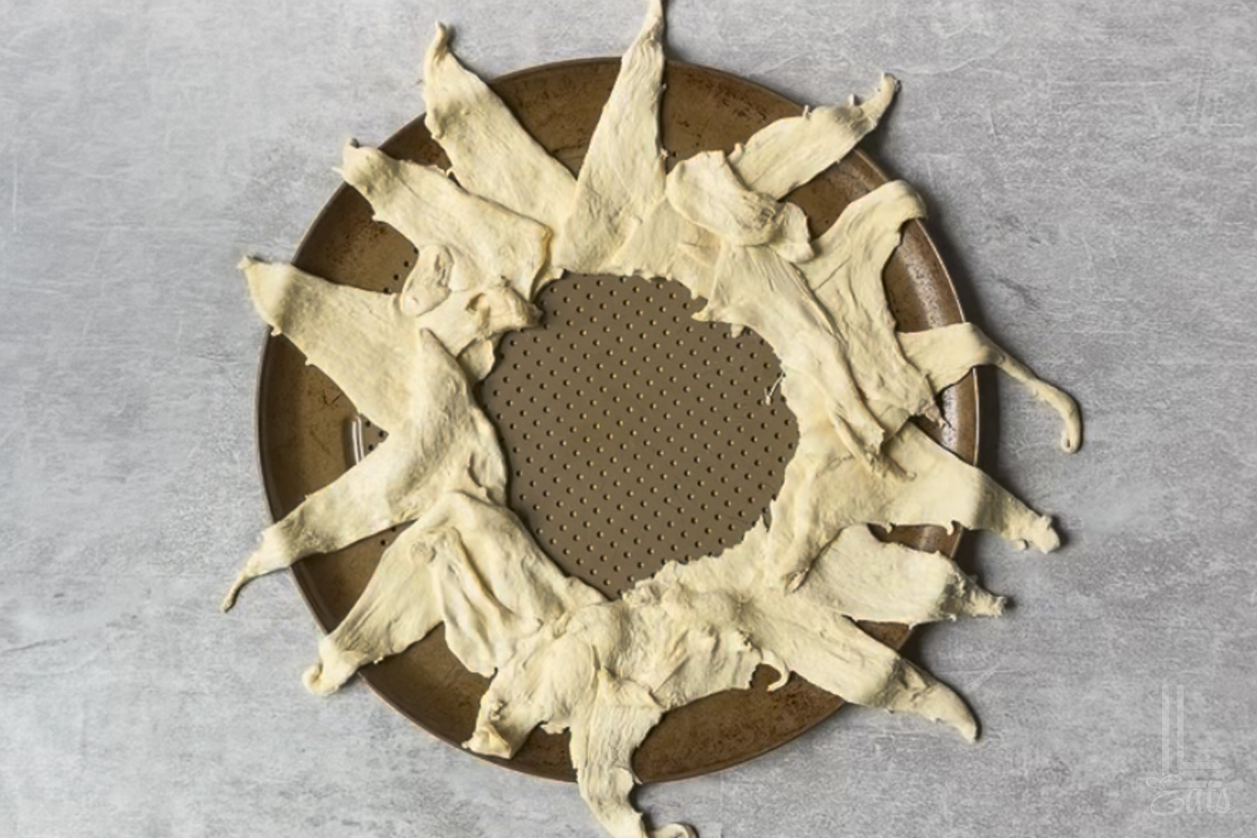 crescent roll dough in a sunburst shape on a round pizza pan.