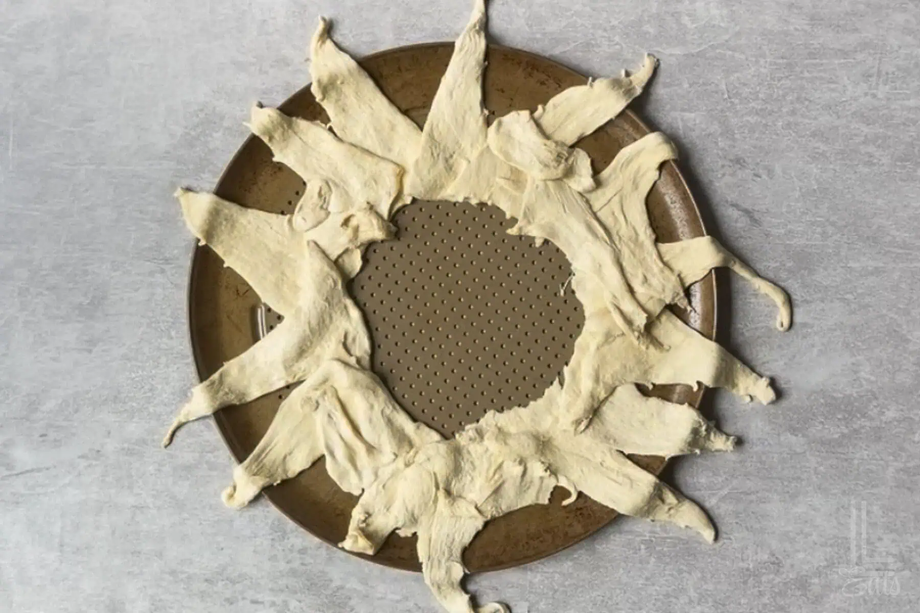 crescent roll dough in a sunburst shape on a round pizza pan.