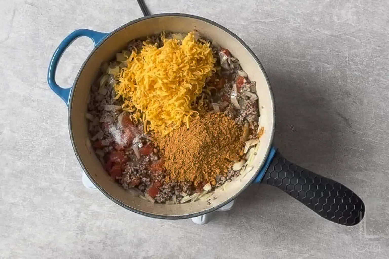 cheese, rotel tomatoes, and taco seasoning added to the ground beef and onions in the skillet.