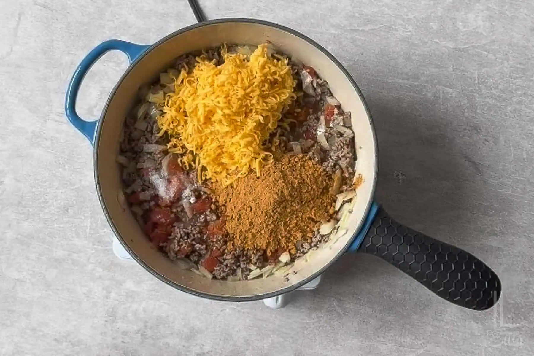 cheese, rotel tomatoes, and taco seasoning added to the ground beef and onions in the skillet.