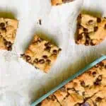 Peanut butter cookie bars with chocolate chips on parchment paper with text overlay.