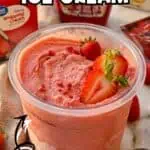 Close-up of homemade strawberry ice cream in a clear cup with fresh strawberries.