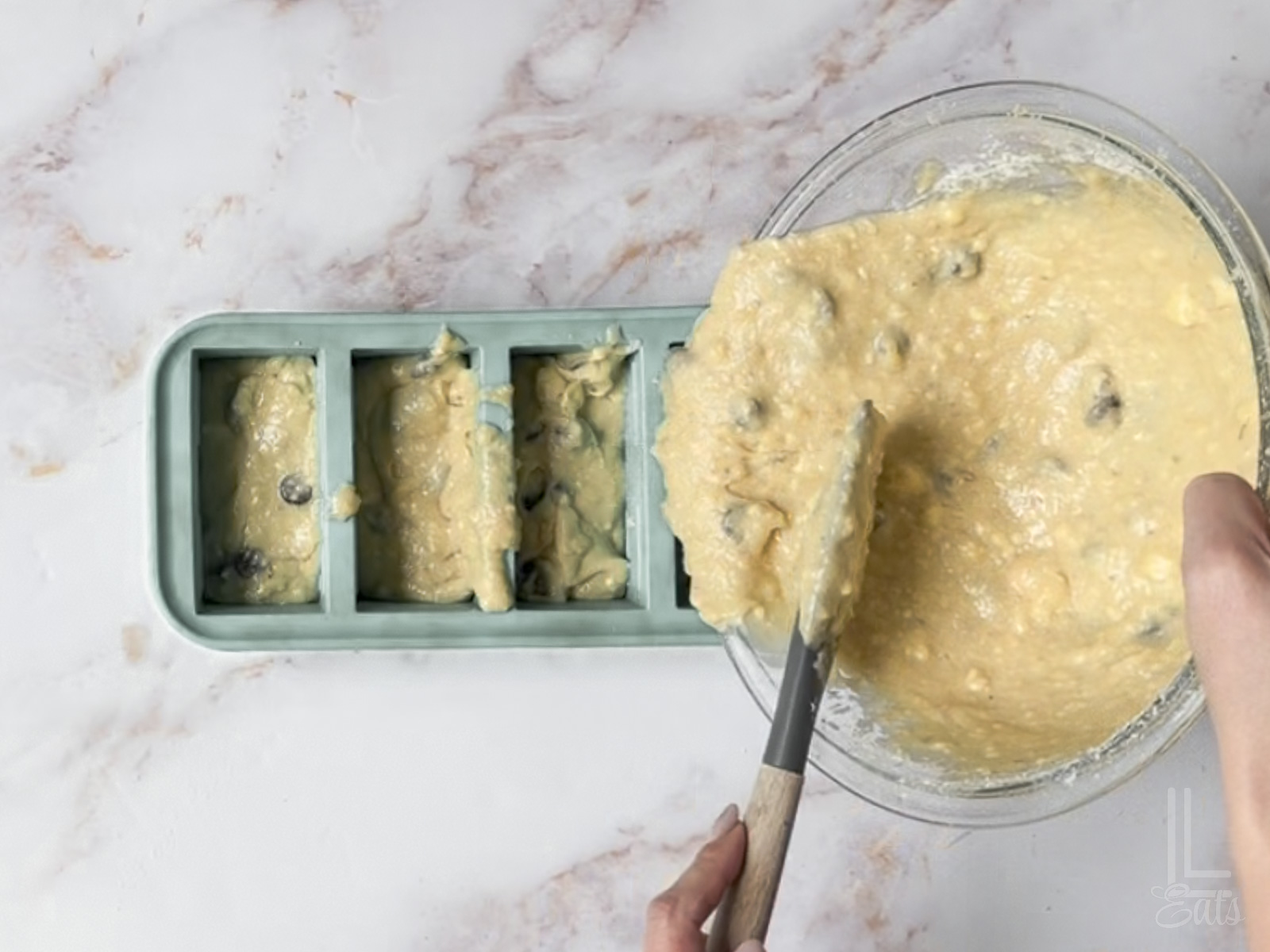 adding the chocolate chip banana bread batter to a loaf pan.