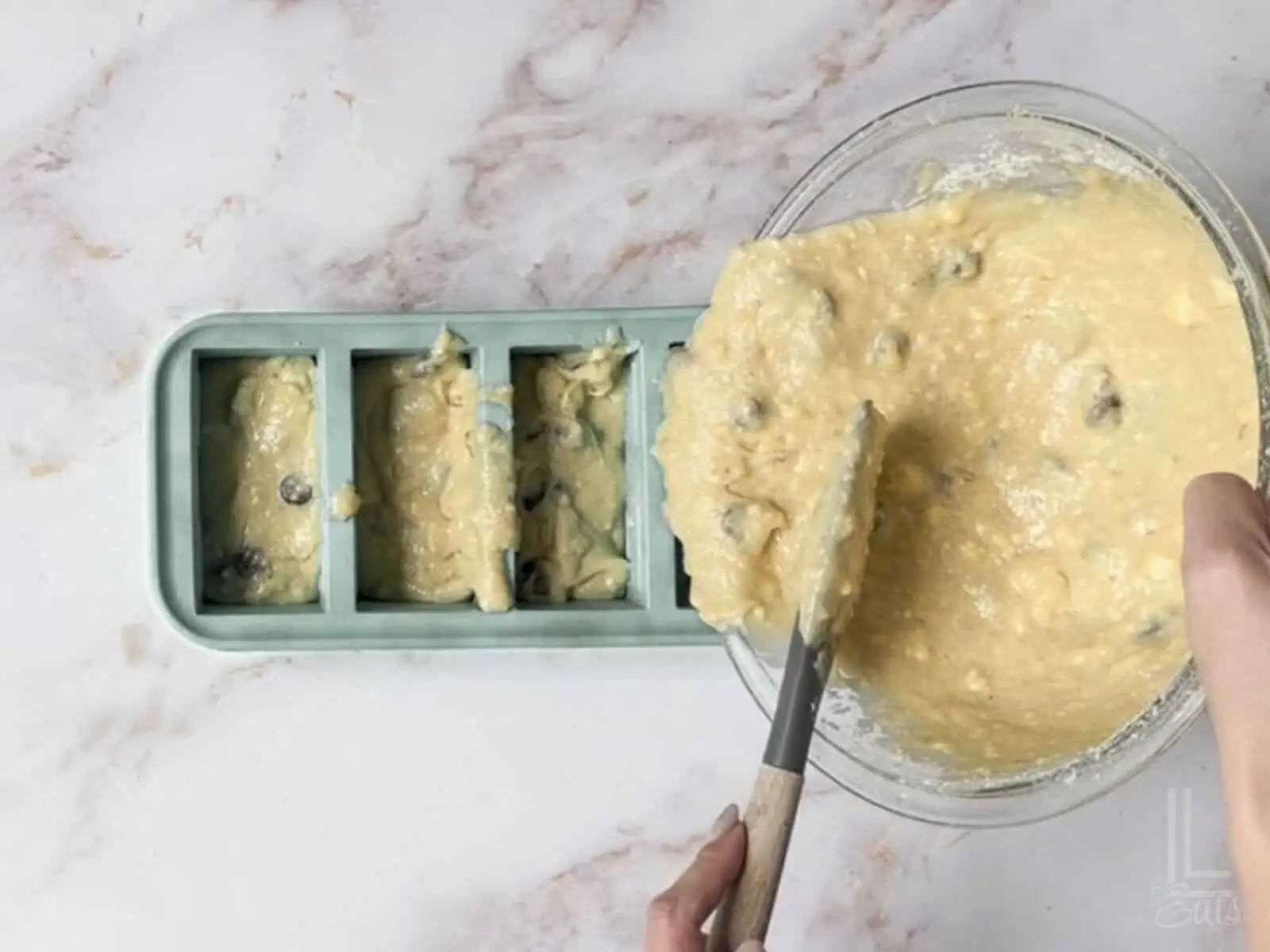 adding the chocolate chip banana bread batter to a loaf pan.