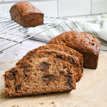 chocolate chip banana bread cut into slices and stacked on a cutting board.