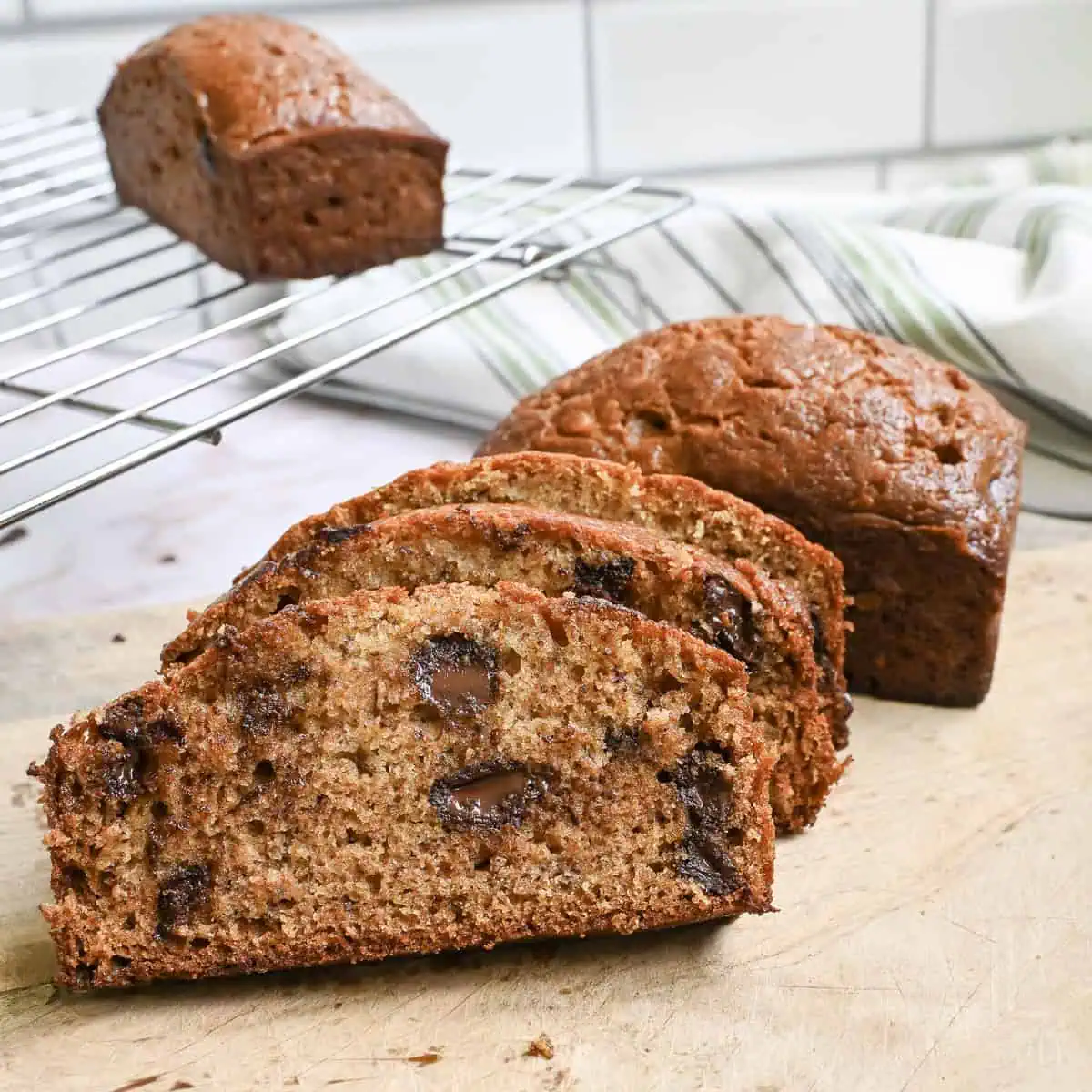 chocolate chip banana bread cut into slices and stacked on a cutting board.