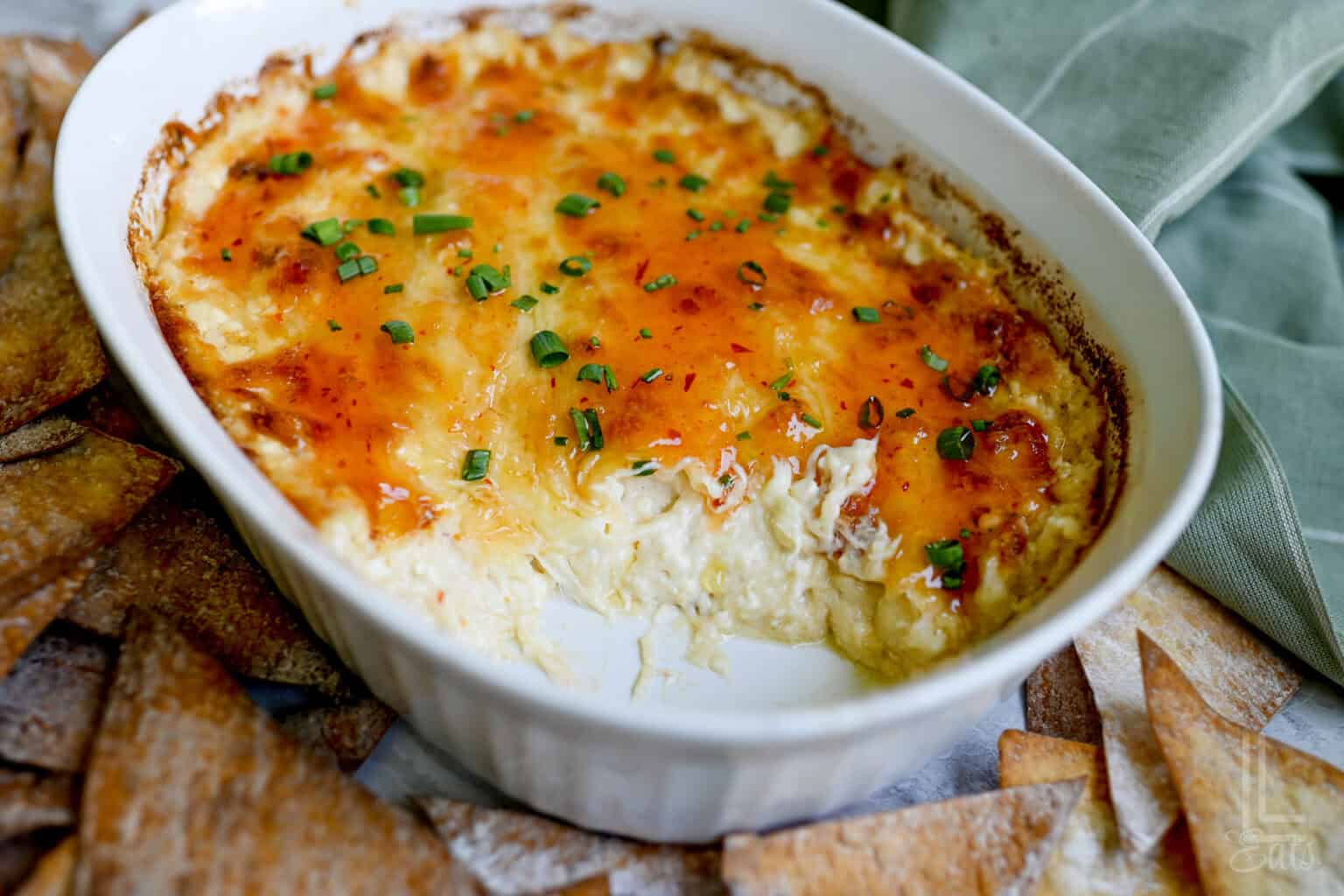 crab rangoon dip after baking, covered in a sweet chili sauce and green onions.