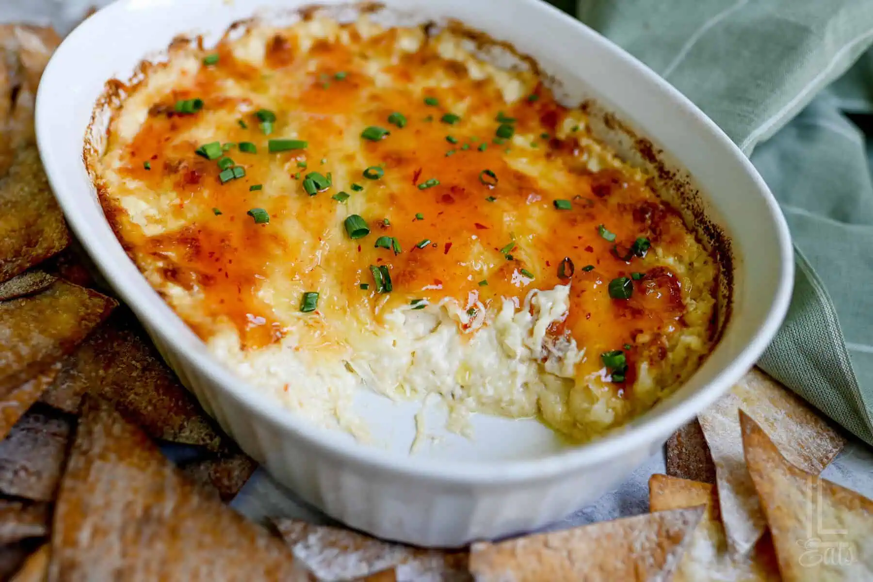 crab rangoon dip after baking, covered in a sweet chili sauce and green onions.