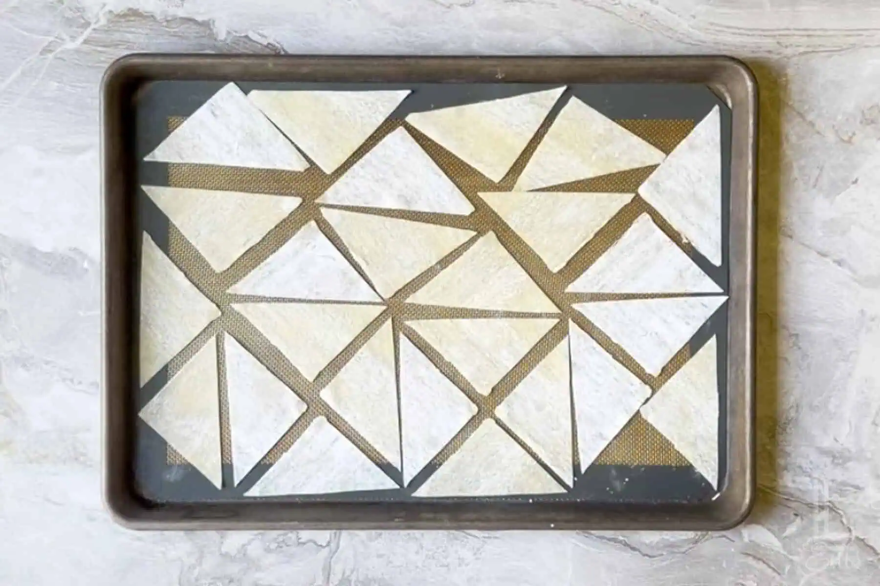 triangles of wonton wrappers on a baking sheet.