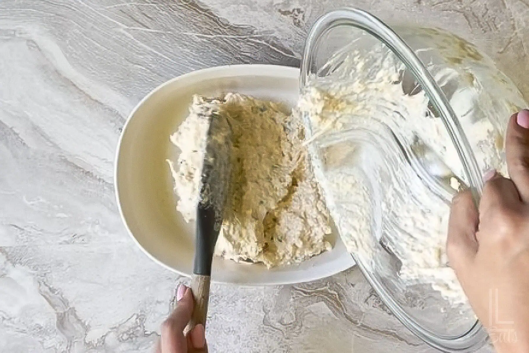 pouring the creamy crab rangoon dip into a baking dish.