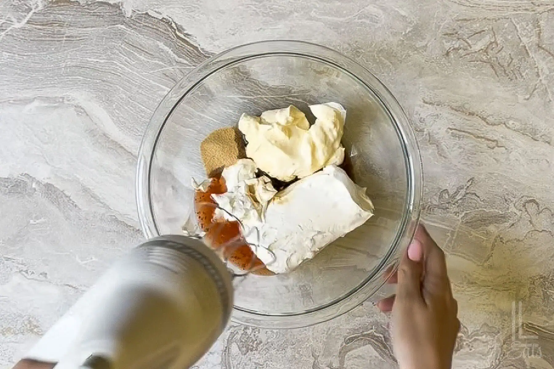 cream cheese, mayo, sour cream, spices, soy sauce, and chili glaze in a bowl, about to be mixed with a hand mixer.