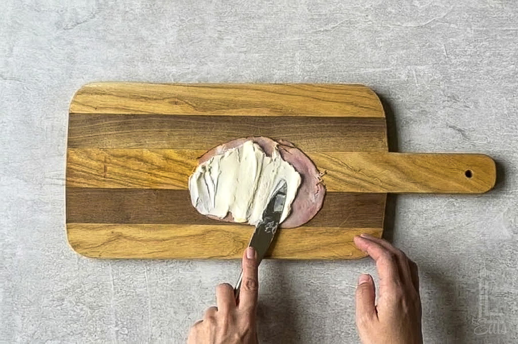spreading a layer of cream cheese on the dried ham.