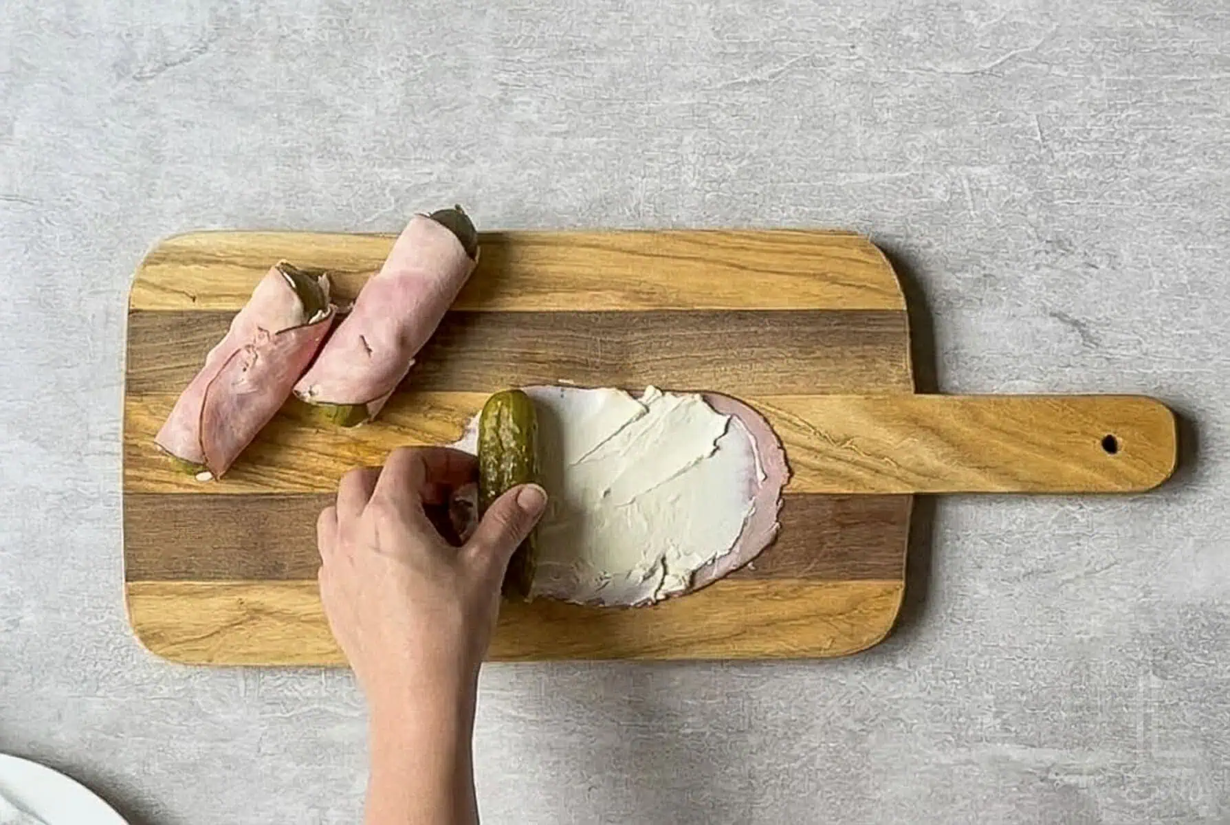 rolling the whole pickle in the ham and cream cheese.